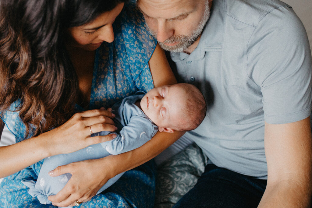 Madre y padre abrazando a su bebé recién nacido, sesión de fotografía familiar íntima